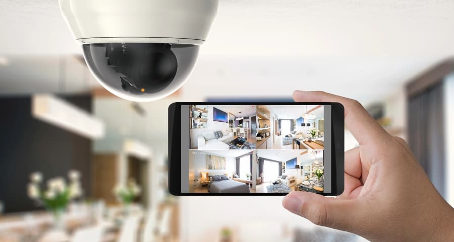 Homeowner holding smartphone with video feed from security cameras in Miami